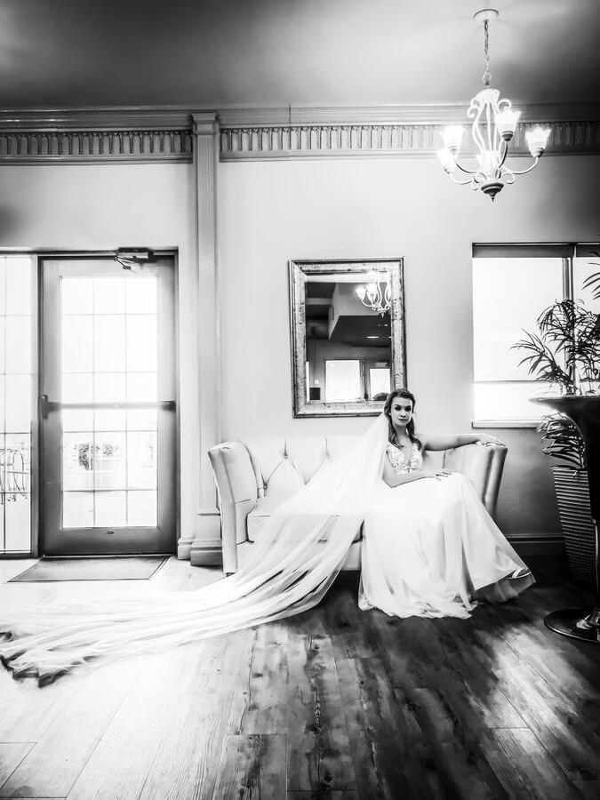 Bride sitting on old style chair with veil extended behind her