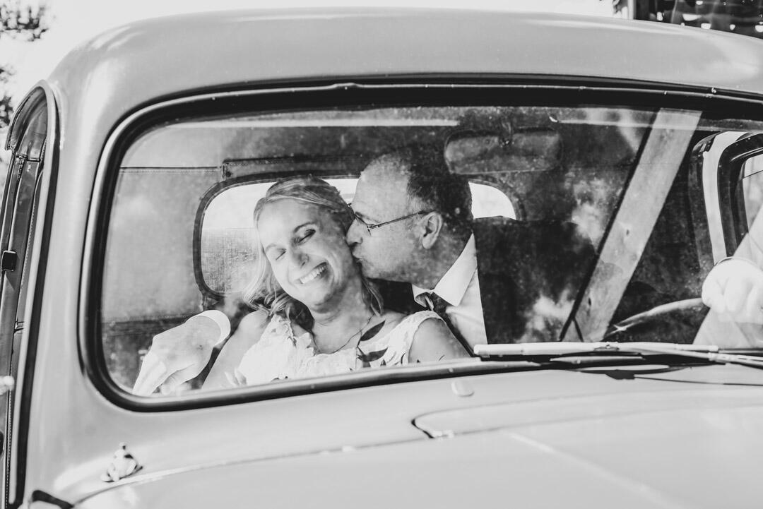 Wedding - Bride & Groom in a car, with groom kissing brides cheek