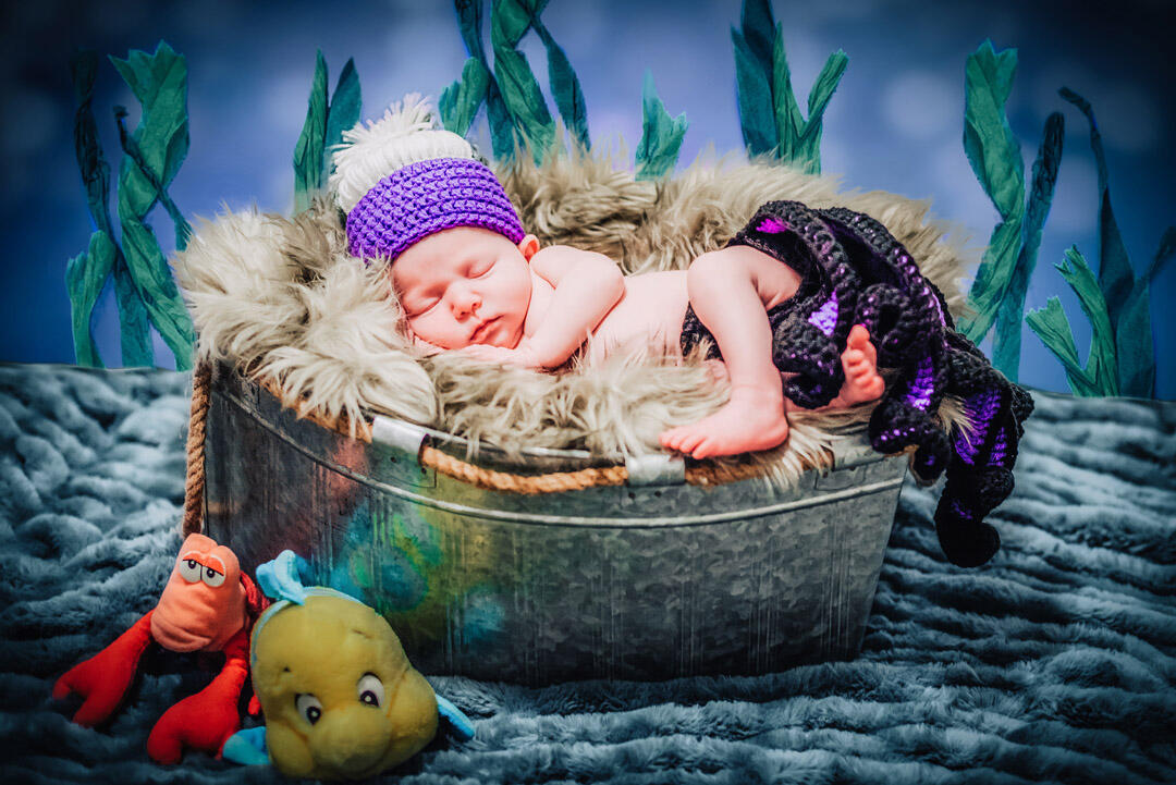 Baby - newborn wearing ursula crochet hat and diaper cover, sleeping with a sea backdrop