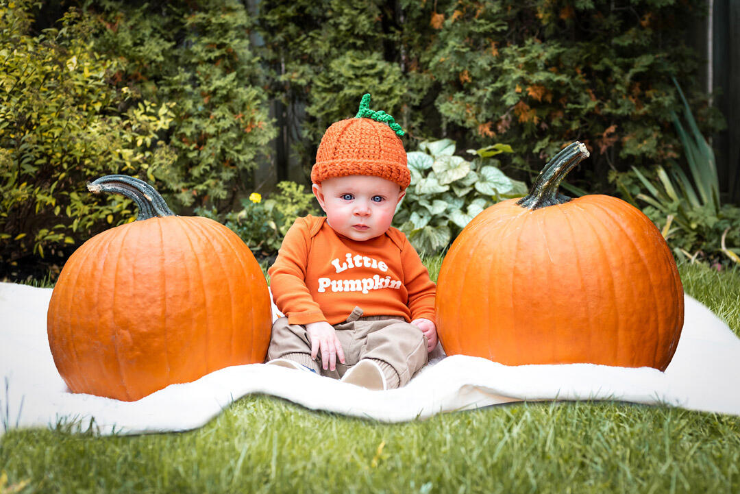 Untitled Baby - baby sitting in between two pumpkins