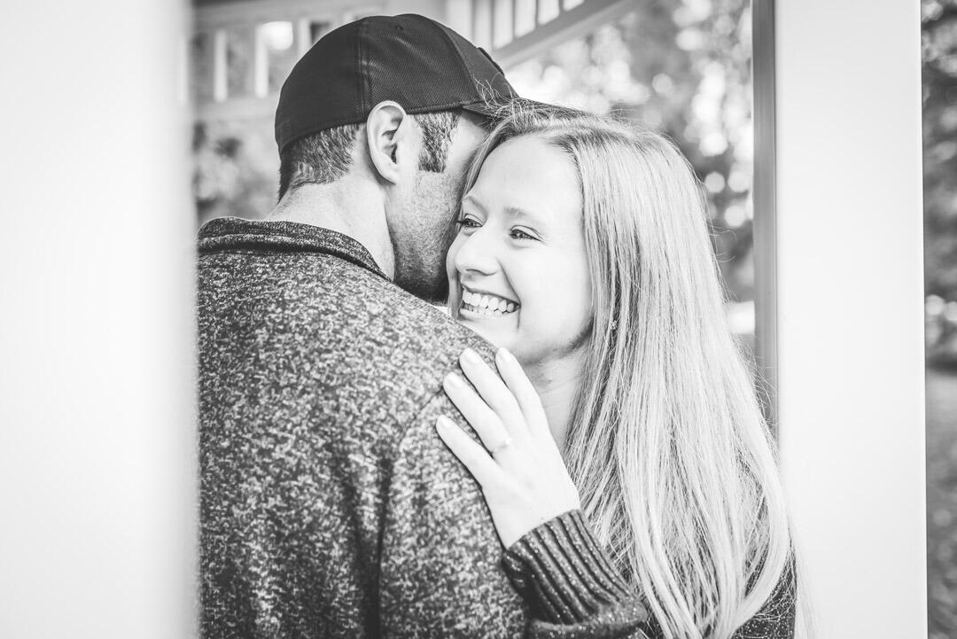 Couple - man whispering into woman's ear while she laughs